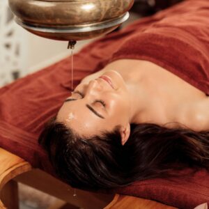 Oil pouring over a woman's forehead as part of Shirodhara therapy